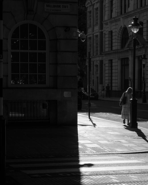 A street scene in an urban area featuring multi-storey classical-style buildings on both sides, with a blue van parked at the curb. The van, associated with Man with Van Millbank, has an open side doo